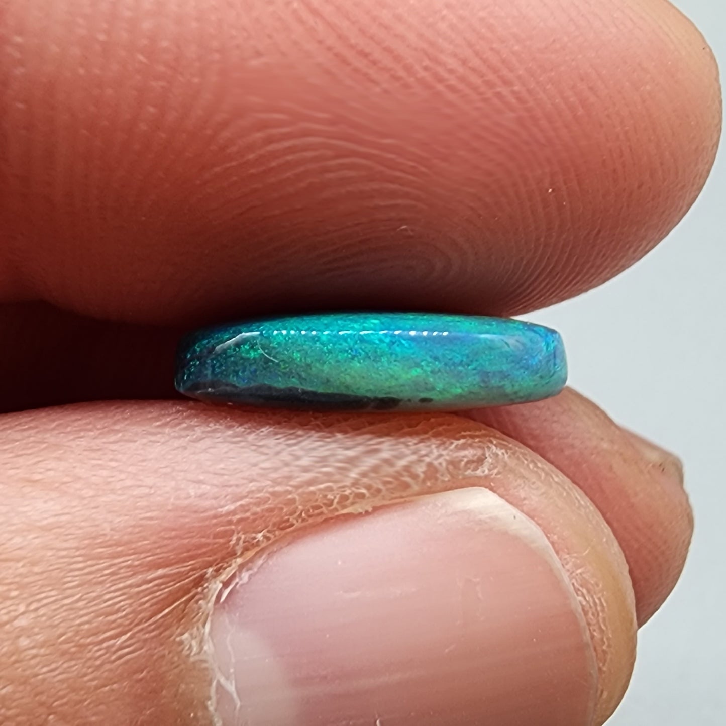 3.0ct teal colored black opal with a striated moss pattern