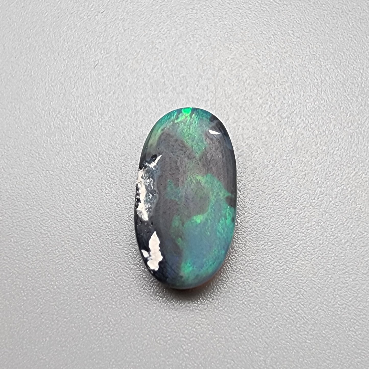 3.0ct teal colored black opal with a striated moss pattern