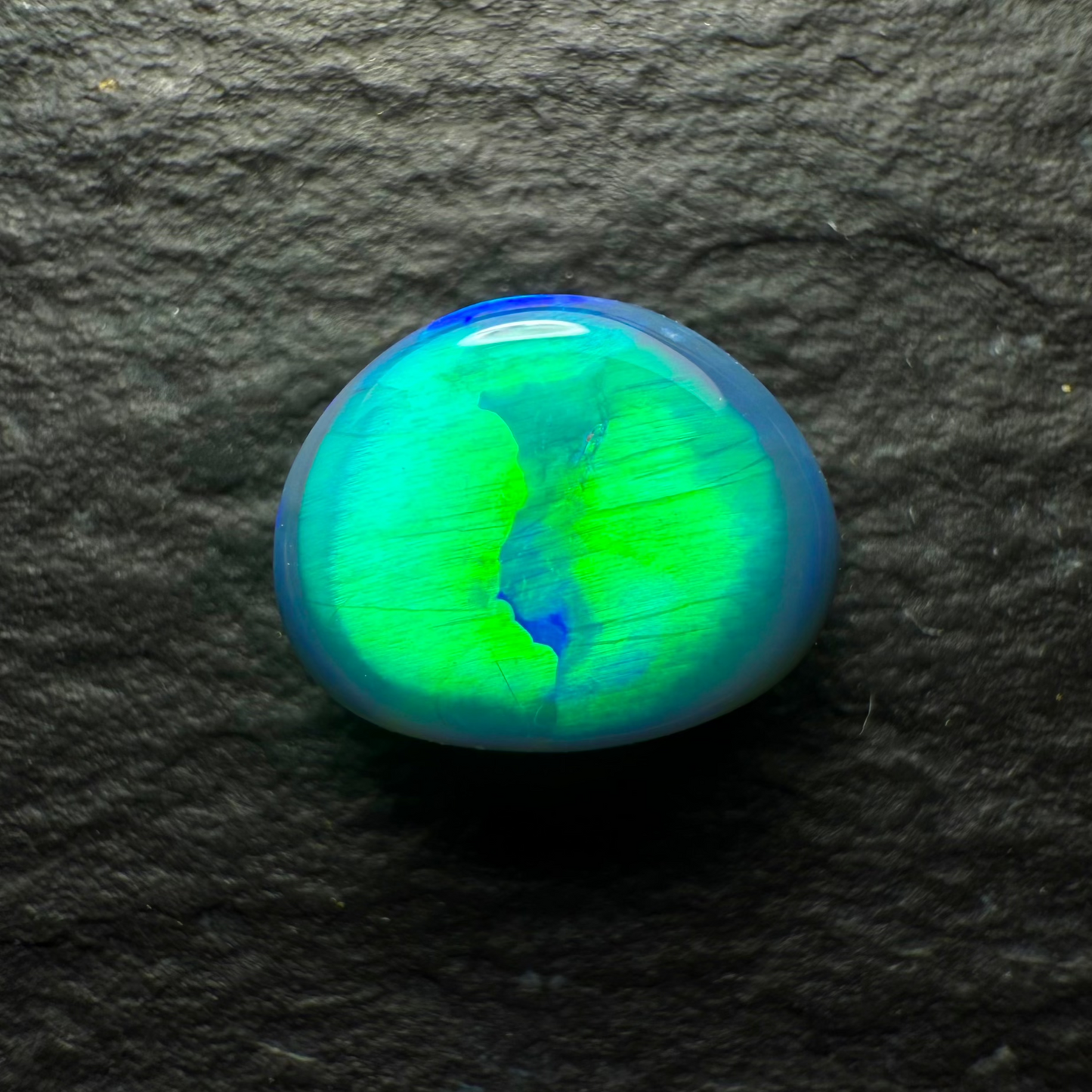 0.74ct Top Gem Black Opal With Brilliant Green Rolling Broadflash Pattern Creating an Eye Like structure In The Center Of The Stone