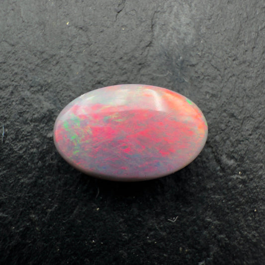 Multicolored opal stone on a dark textured background