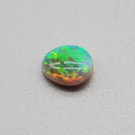 1.3cts Dark opal with a soft teardrop shape and vivid Green-yellow color play.