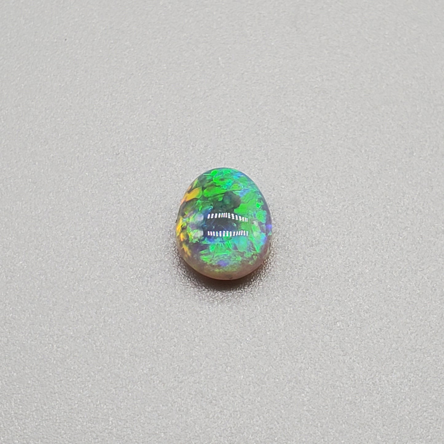 1.3cts Dark opal with a soft teardrop shape and vivid Green-yellow color play.