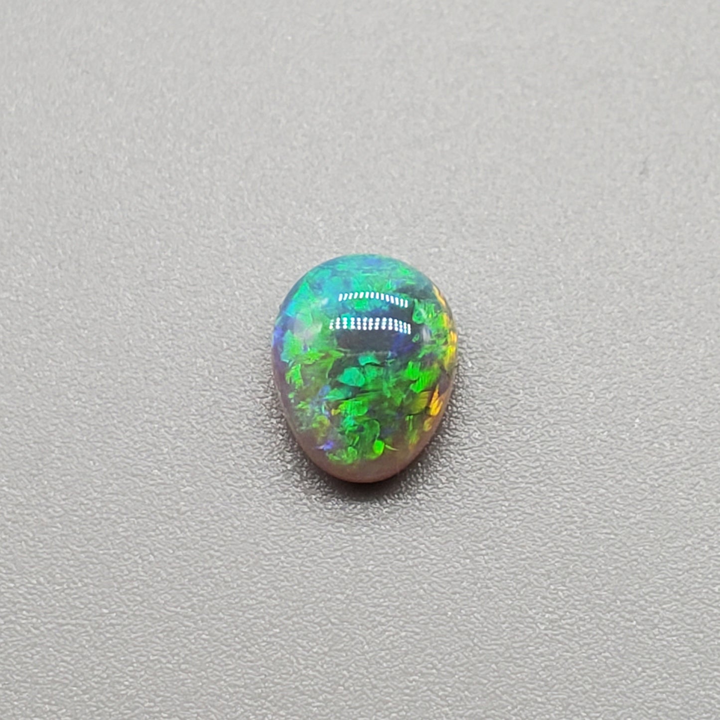 1.3cts Dark opal with a soft teardrop shape and vivid Green-yellow color play.