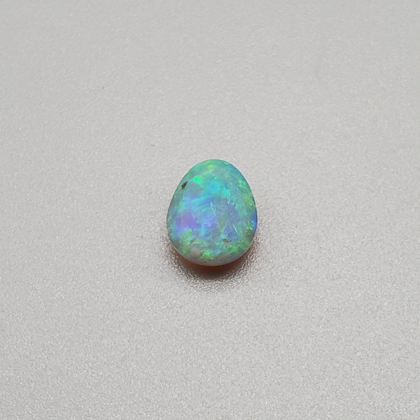 1.3cts Dark opal with a soft teardrop shape and vivid Green-yellow color play.