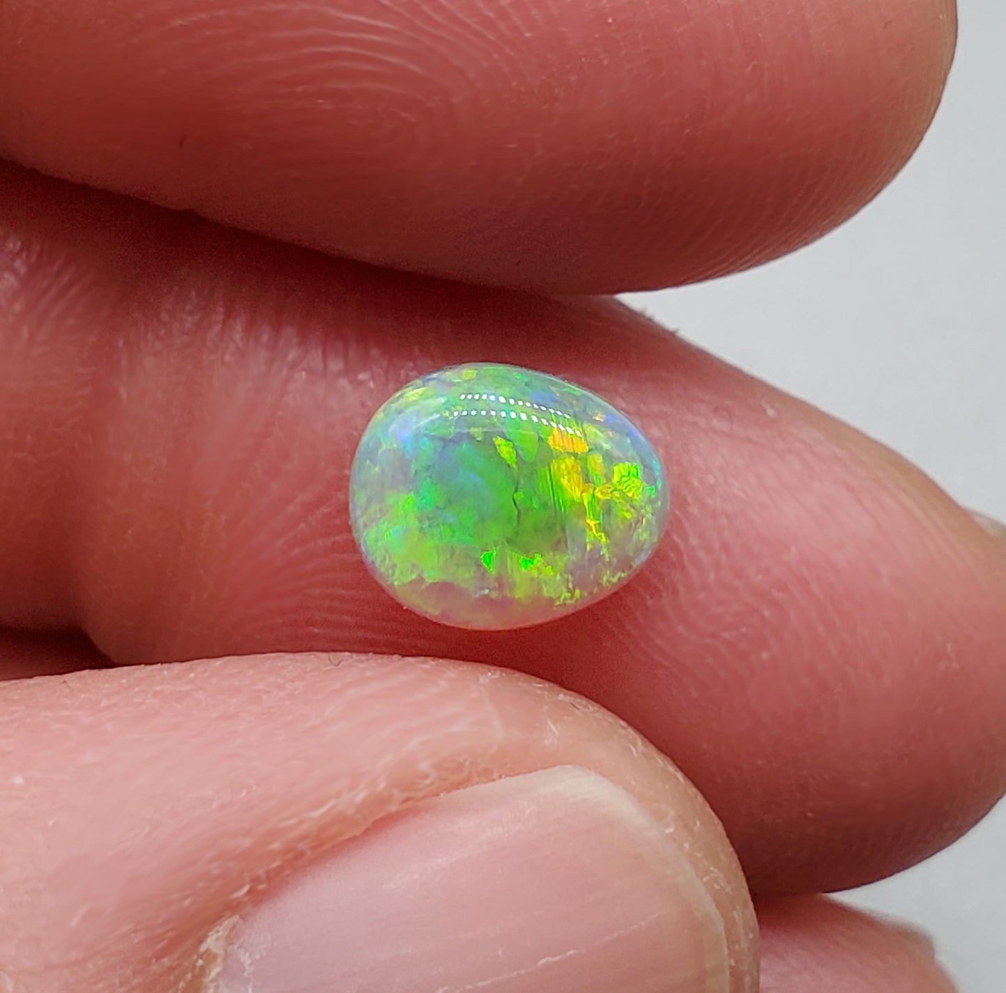 1.3cts Dark opal with a soft teardrop shape and vivid Green-yellow color play.