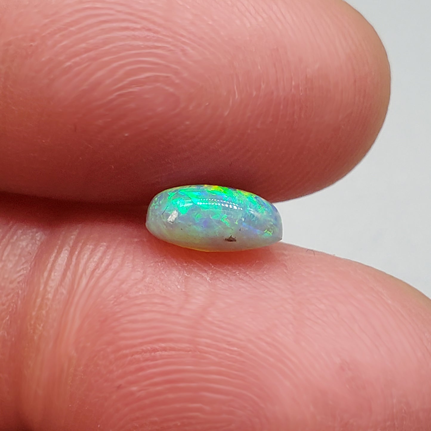 1.3cts Dark opal with a soft teardrop shape and vivid Green-yellow color play.