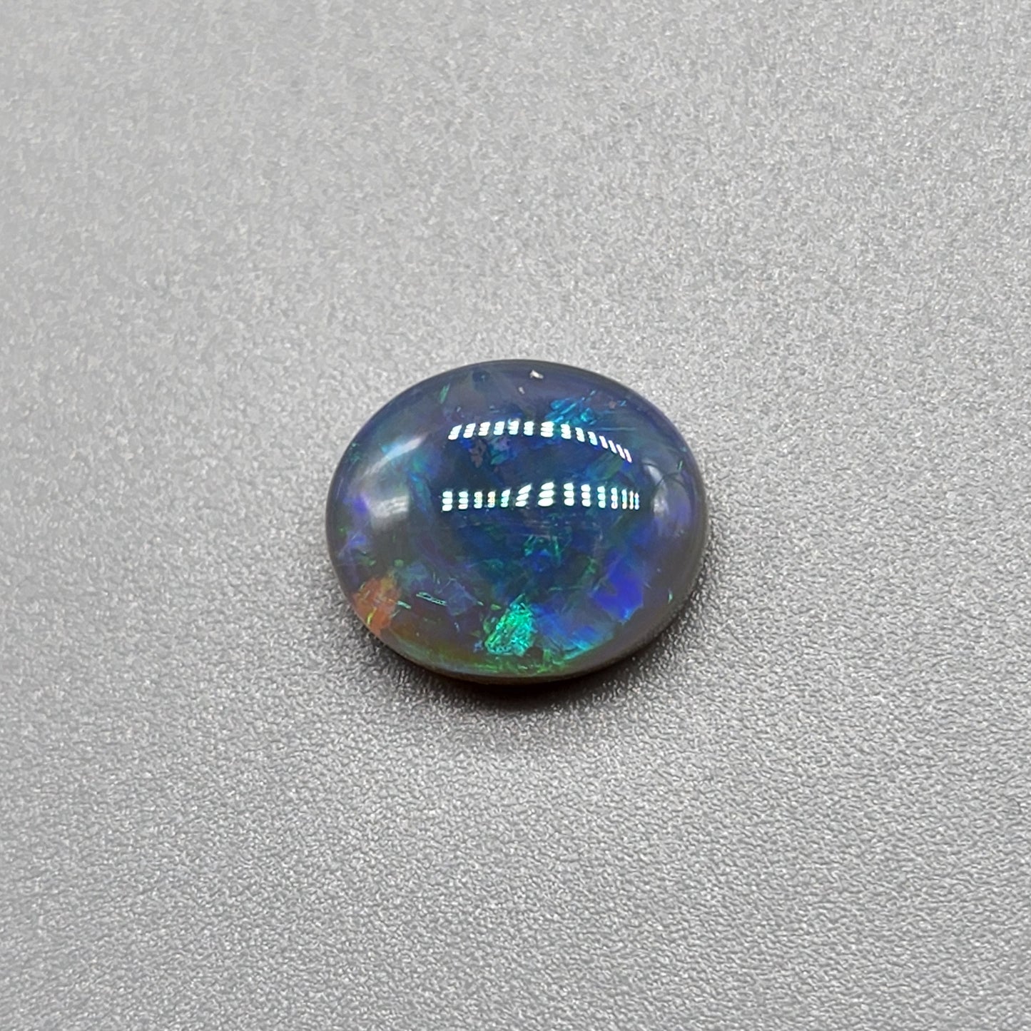 2.5ct Dark opal with a a dark blue base overlane by a minty green chaff pattern