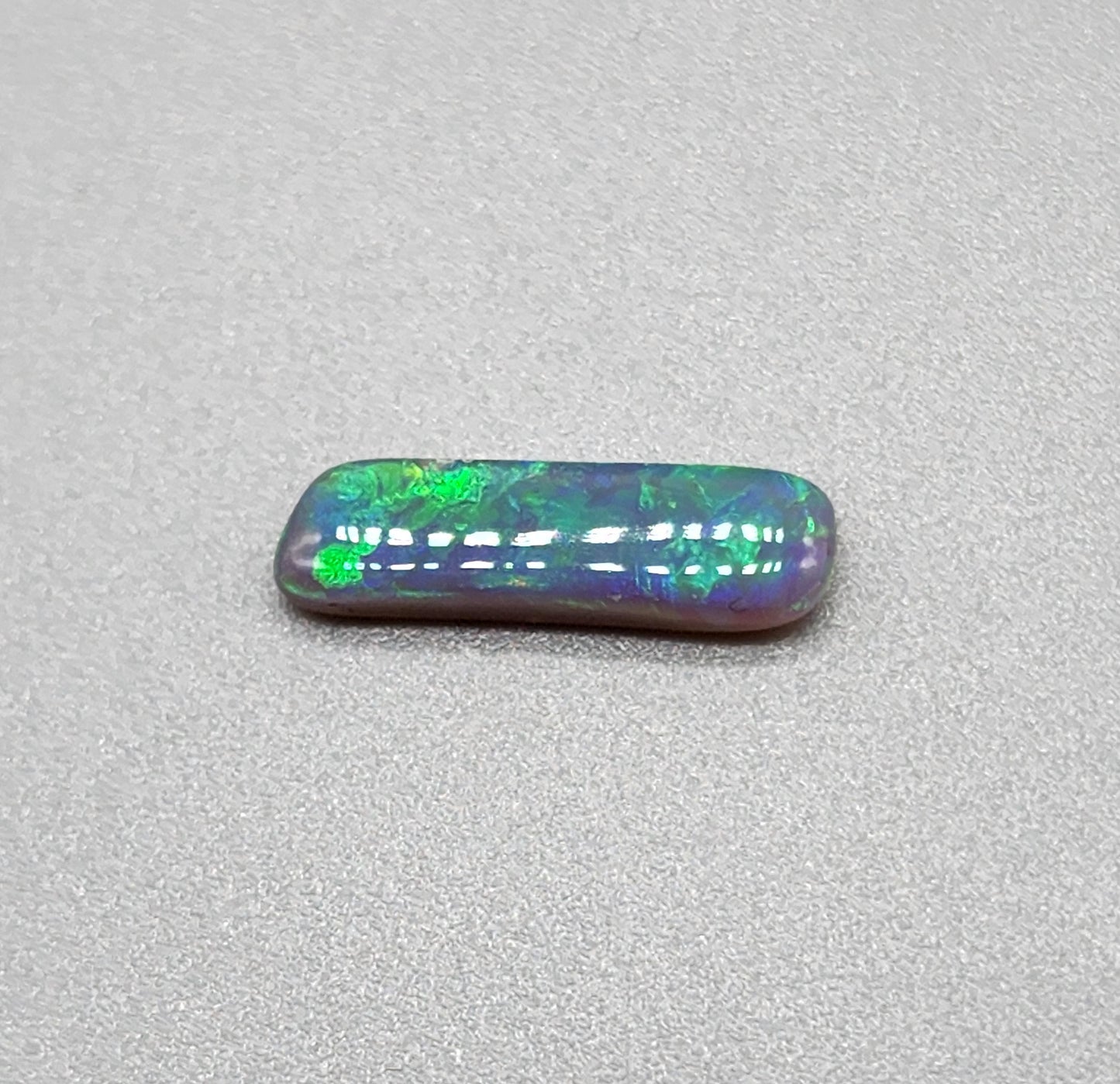 1.3cts Dark opal with elongated freeform shape and blue and green color play