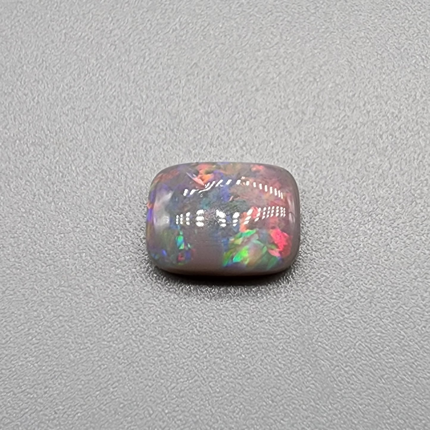 1.75cts dark opal with pink-multicolor and good color dispersal on a soft cushion cut