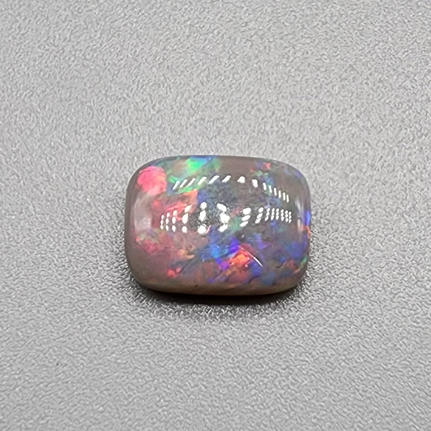 1.75cts dark opal with pink-multicolor and good color dispersal on a soft cushion cut