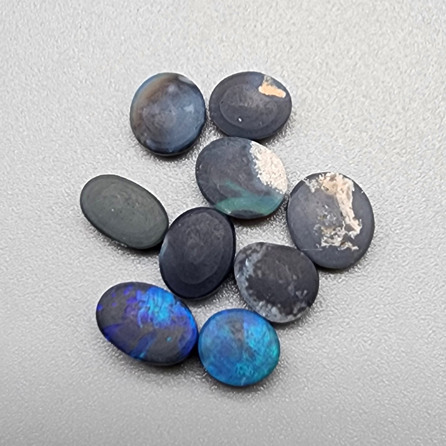 An assortment of accessible black opals with an attractive array of blues, greens and teals